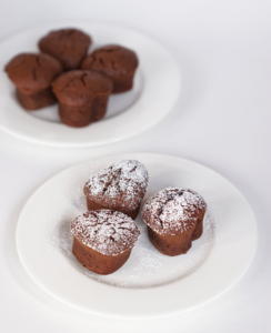 drei Muffins mit Schokolade und Nougat auf weißem Teller, mit Puderzucker bestäubt