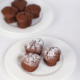 drei Muffins mit Schokolade und Nougat auf weißem Teller, mit Puderzucker bestäubt