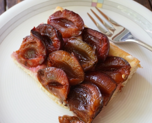 Stück Zwetschgenkuchen auf Kuchenteller mit Kuchengabel